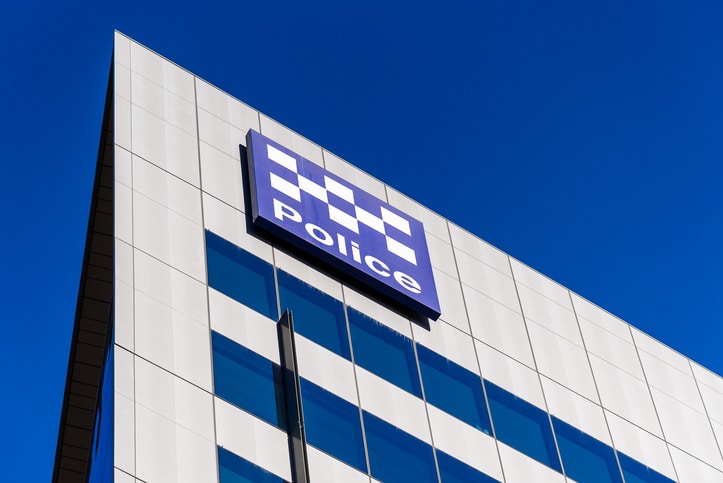 A blue and white police sign on the side of a building with the checkered police pattern