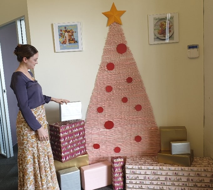 young woman placing presents in front of Christmas tree