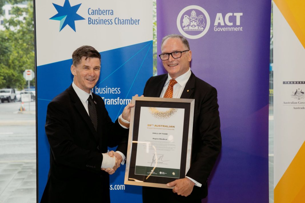 two men in suits and ties shaking hands and holding award