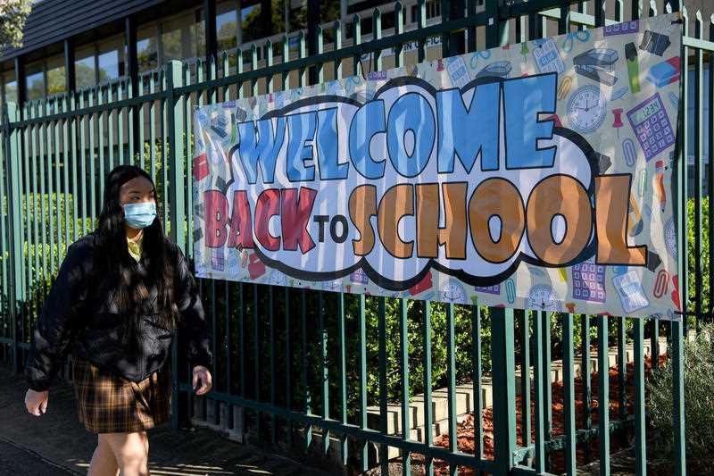A welcome Back to School banner hangs on the fence as students in years 2-11 return to school at Fairvale High School in Sydney, Monday, October 25, 2021.