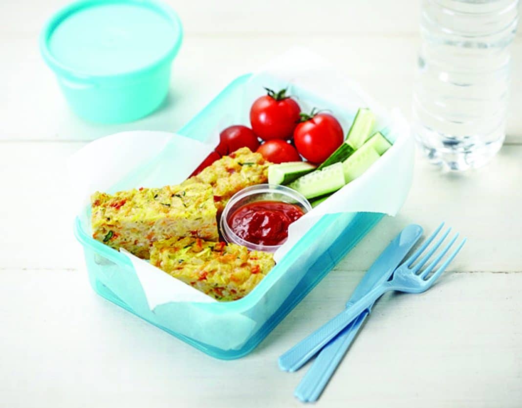 vegetable frittata slices in a lunch box with cherry tomatoes and zucchini sticks