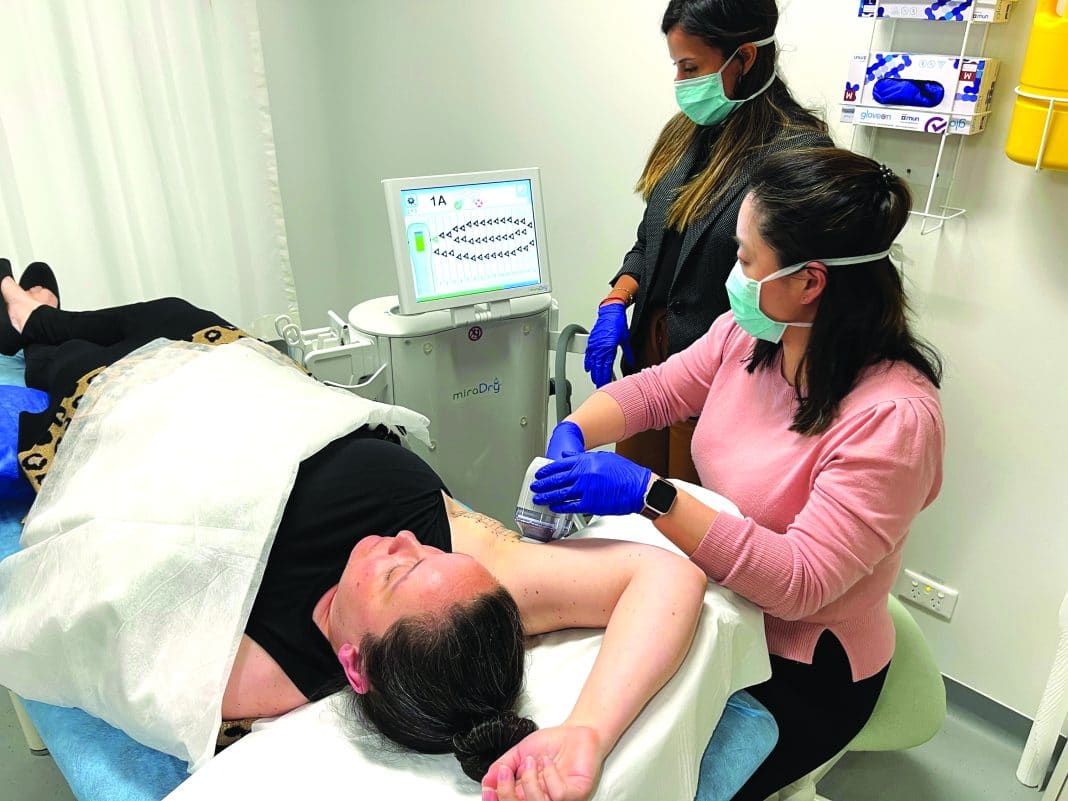 Female doctor is seen using therapeutic device on woman's underarms to reduce sweating