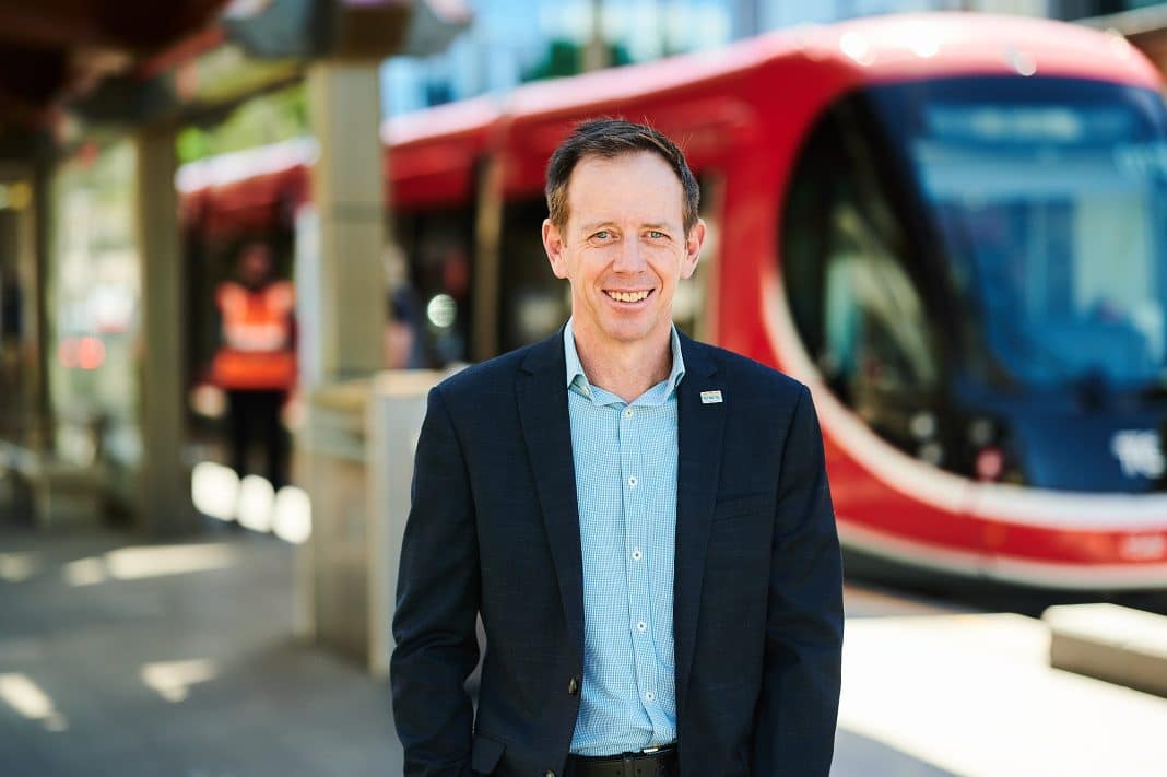 ACT Greens leader Shane Rattenbury is seen standing on a light rail platform in Canberra with a light rail vehicle in the background