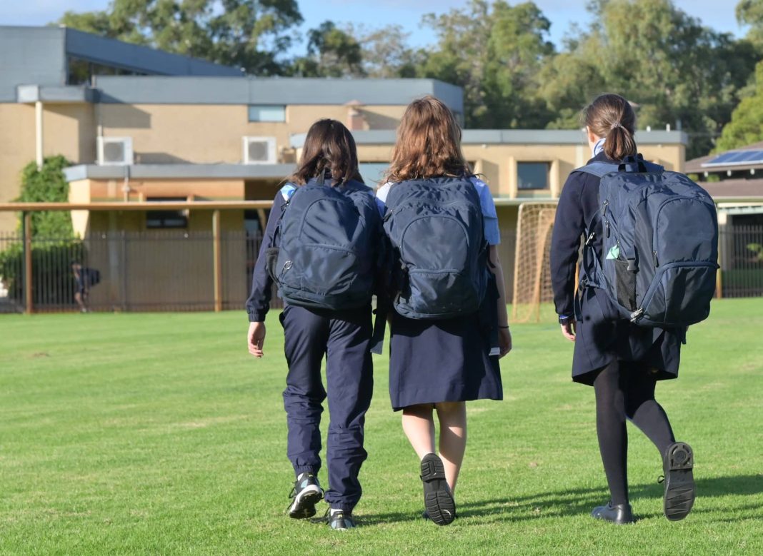three school children with backpacks walking to school
