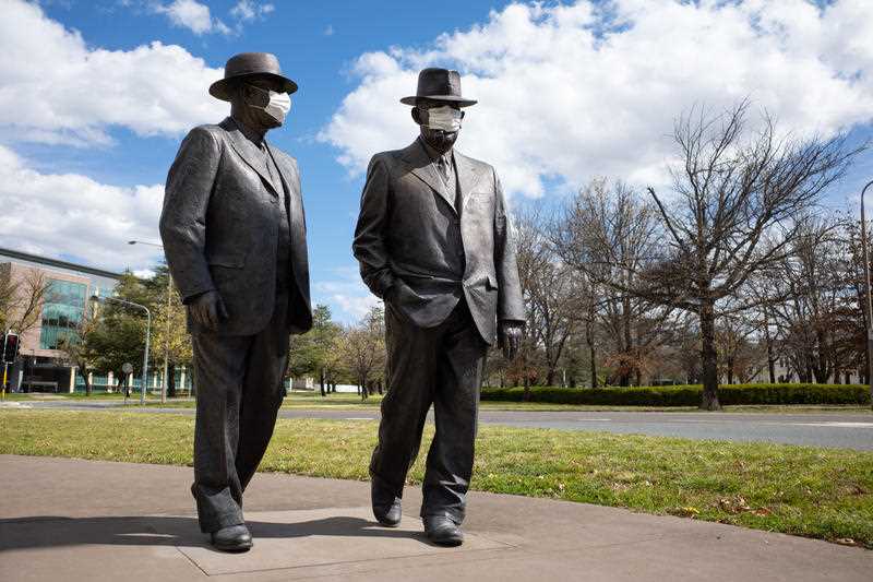 The statue of the late Australian Prime Minister John Curtin and Australian Treasurer Ben Chifley are seen with a face mask in Canberra