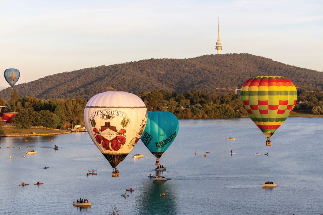 hot air balloons floating near boats on lake Burley Griffin in Canberra
