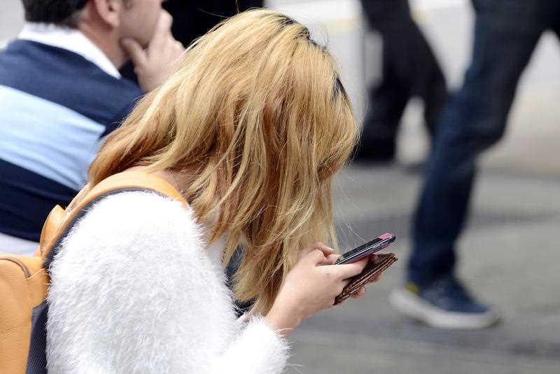 A young woman looks down at her mobile phone