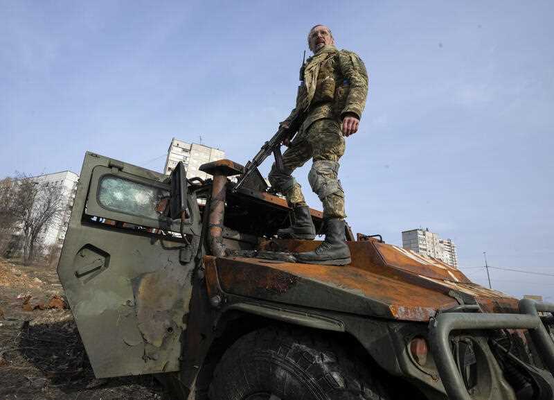 A Ukrainian soldier stands a top a destroyed Russian APC after recent battle in Kharkiv, Ukraine, Saturday, March 26, 2022