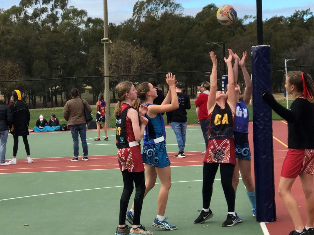 teenage girls playing netball, some wearing skirts, others wearing leggings