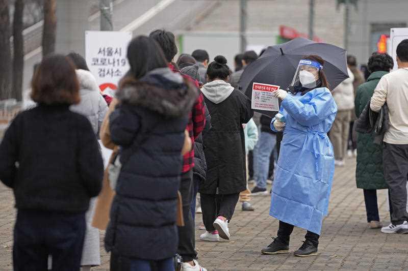 A medical worker holds a sign for visitors to prepare for the coronavirus tests at a temporary screening clinic for coronavirus in Seoul, South Korea