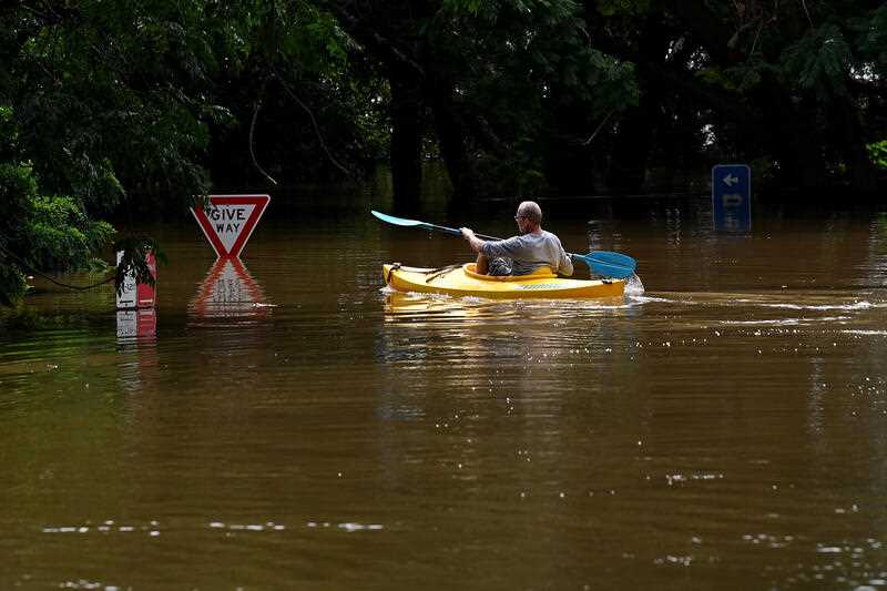 A resident paddles through floodwater as a road is submerged in Windsor, north-west of Sydney, Wednesday, March 9, 2022