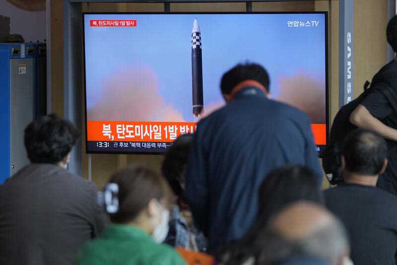 People watch a TV screen showing a news program reporting about North Korea's missile launch