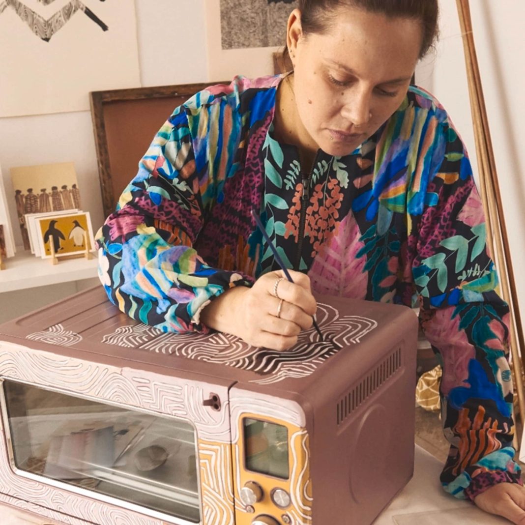 Sydney based artist and Yuwaalaraay woman Lucy Simpson painting on a Breville microwave oven.
