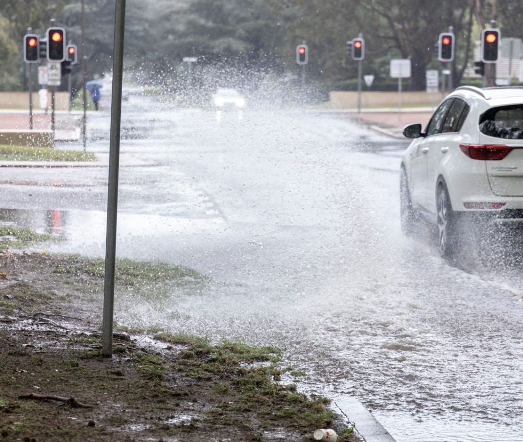 cars seen driving through puddle at signalised intersection in Canberra
