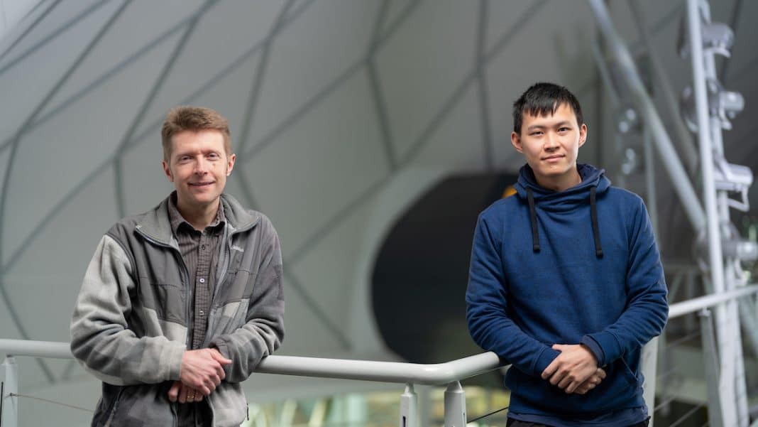 two ANU astronomers standing inside a space telescope