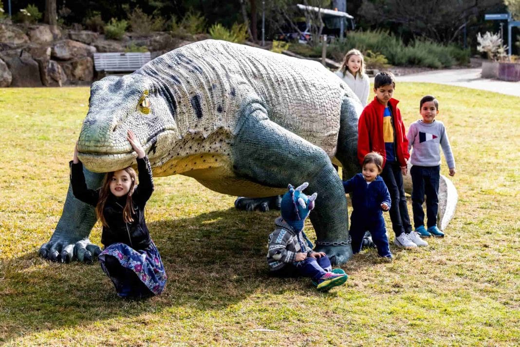 Group of kids playing around a megafauna statue