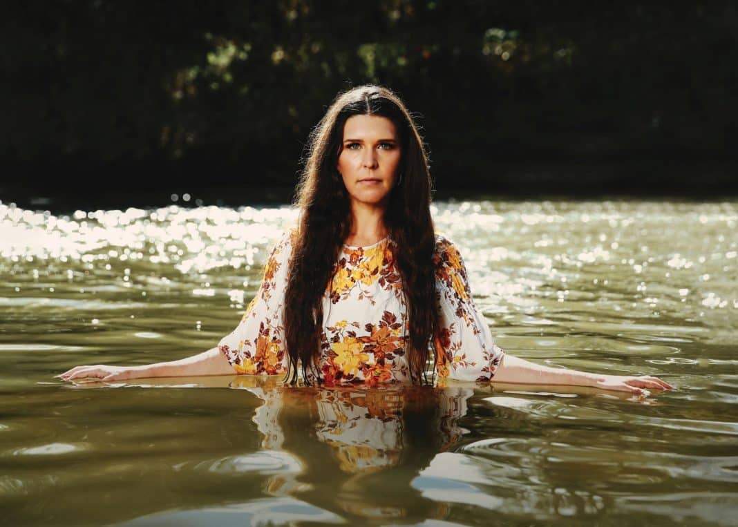 Singer-songwriter Fanny Lumsden standing waist-deep in a pond