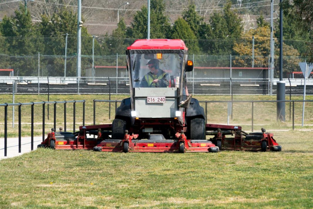 Large ride-on mowing cutting grass on sports fields in Canberra