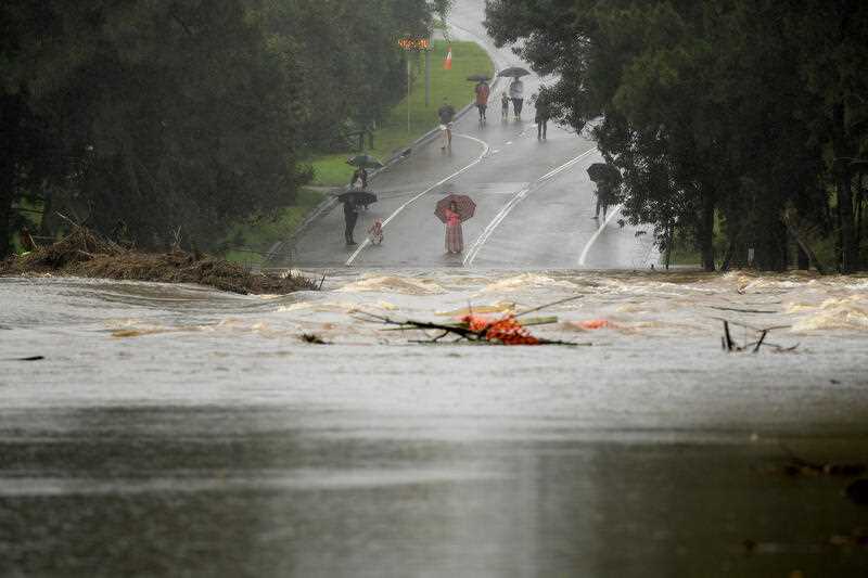 People watch on from the north side as the North Richmond bridge is seen completely submerged by floodwater from the swollen Hawkesbury river, at Richmond, north west of Sydney