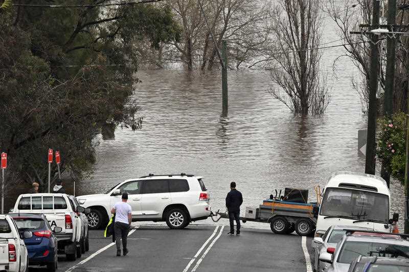 Locals save furniture from a house threatened by floodwaters in Camden in South Western Sydney, Sunday, July 3, 2022