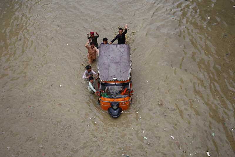 People make their way through a flooded area after heavy monsoon rains in Karachi, Pakistan, 11 July 2022
