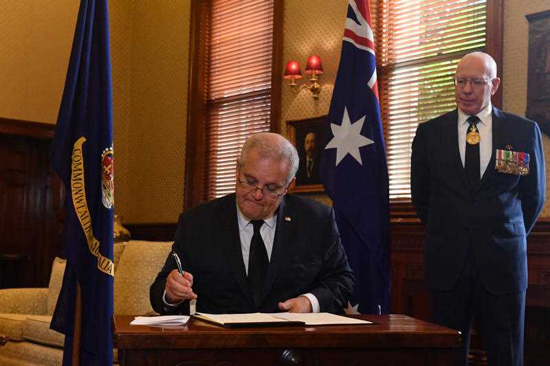 Prime Minister Scott Morrison signs a condolence book as Governor-General David Hurley looks on at Admiralty House following the death of Prince Philip, Duke of Edinburgh, in Sydney, Saturday, April 10, 2021
