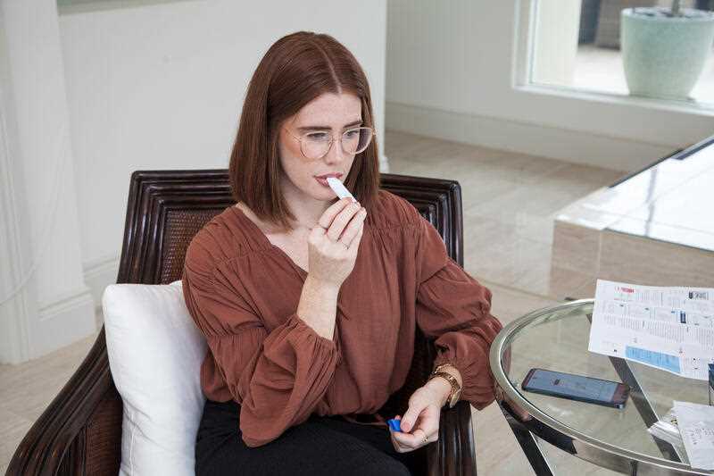 A young woman is seen undertaking a saliva test
