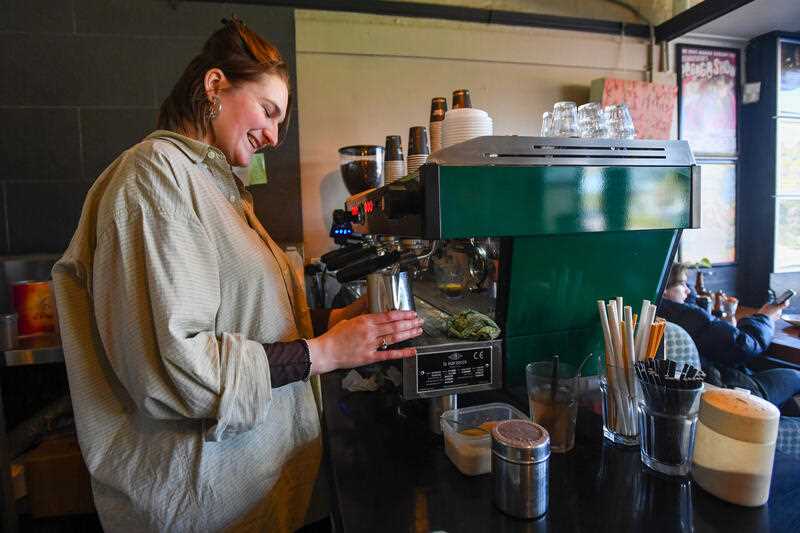 A female barista makes a coffee at a cafe