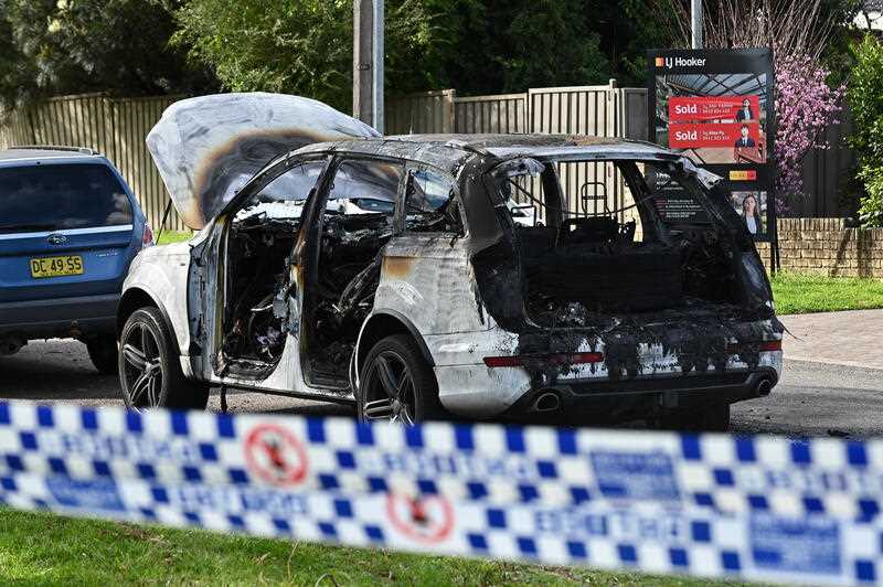 A burnt out car is seen on a street in the suburb of Revesby, Sydney, Sunday, August 14, 2022