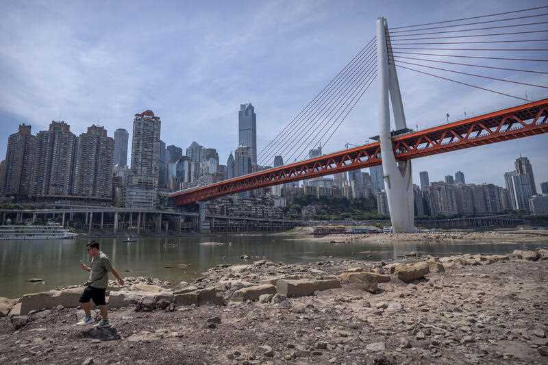 A man walks along the lower than normal bank of the Jialing River in southwestern China