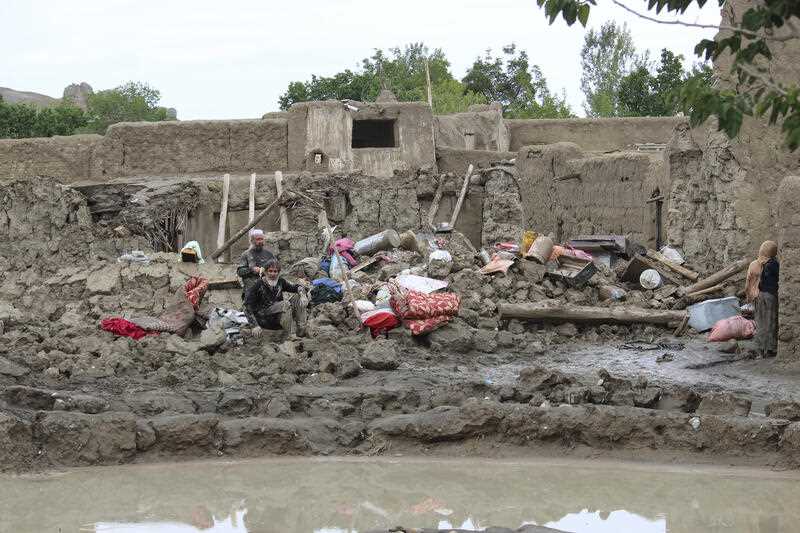People collect their belongings from their damaged homes after heavy flooding in the Khushi district of Logar province south of Kabul, Afghanistan, Sunday, Aug. 21, 2022.