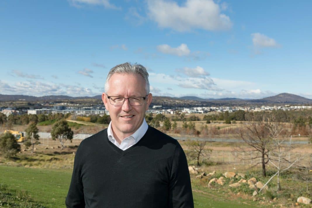 ALP Member for Bean, David Smith, is seen standing outdoors with the suburbs of Canberra visible in the background