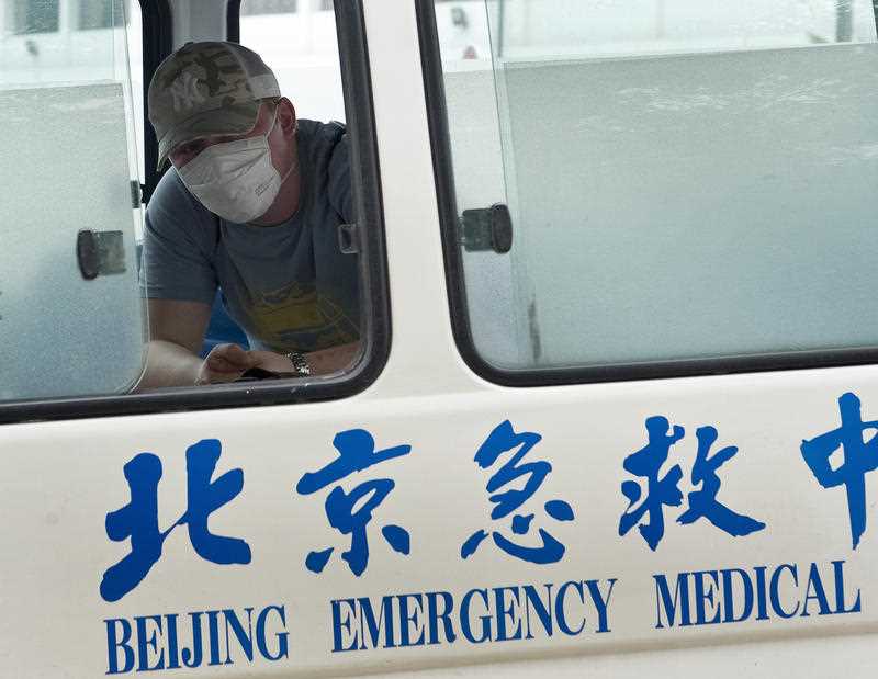 A man wearing a face mask is seen inside a Beijing Emergency Medical ambulance