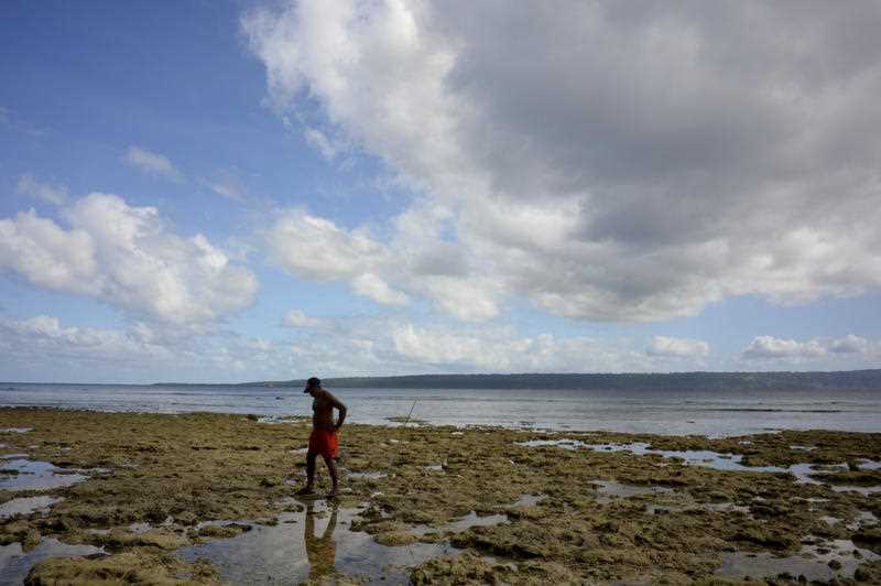 A local man searches for crabs during low tide at a beach in Pango village near Port Vila, Vanuatu
