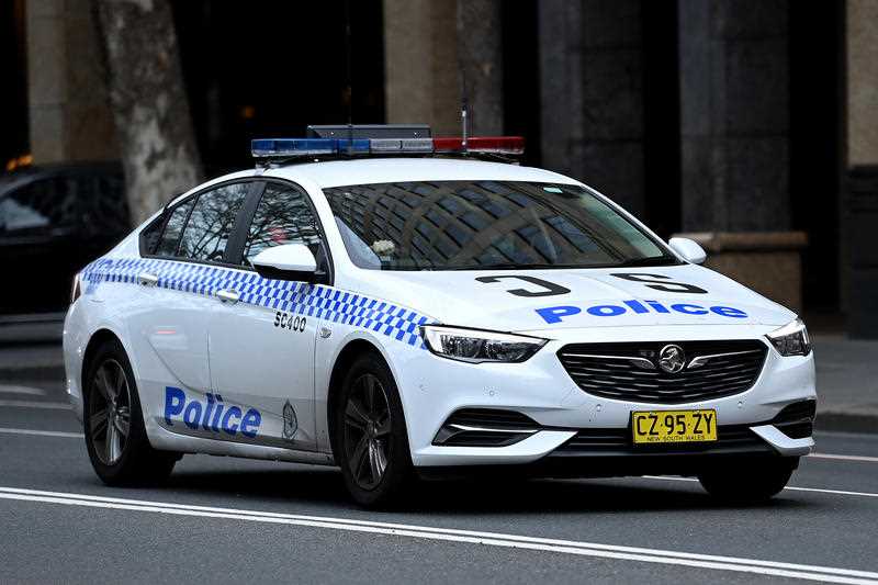 A NSW Police car drives along a street