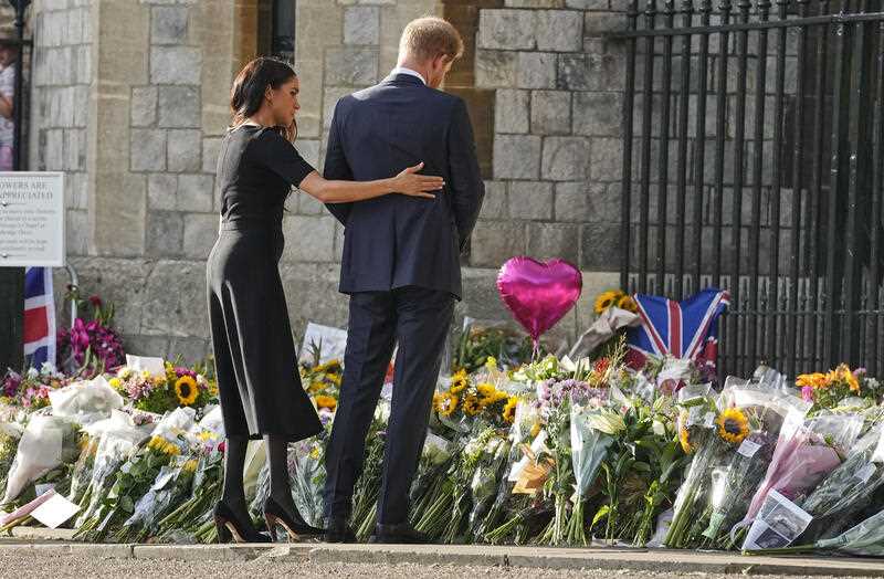 Prince Harry and his wife Meghan look at the floral tributes for the late Queen Elizabeth II outside Windsor Castle