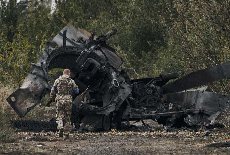 A Ukrainian soldier passes by a Russian tank damaged in a battle in a just freed territory on the road to Balakleya in the Kharkiv region, Ukraine, Sunday, Sept. 11, 2022