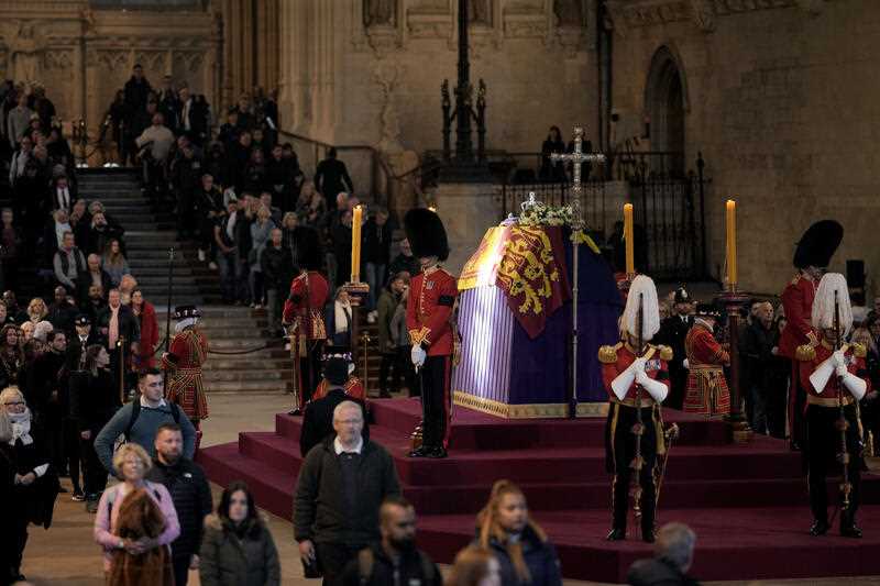 A ray of sun shines on the coffin as members of the public file past the coffin of Queen Elizabeth II, draped in the Royal Standard with the Imperial State Crown and the Sovereign's orb and sceptre, lying in state on the catafalque in Westminster Hall, at the Palace of Westminster, in London, Sunday, Sept. 18, 2022, ahead of her funeral on Monday