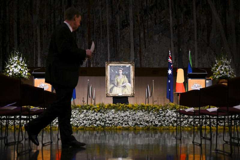 A guest is seen near a portrait of Queen Elizabeth II as he arrives to attend a national memorial service for Queen Elizabeth II at Parliament House in Canberra, Thursday, September 22, 2022