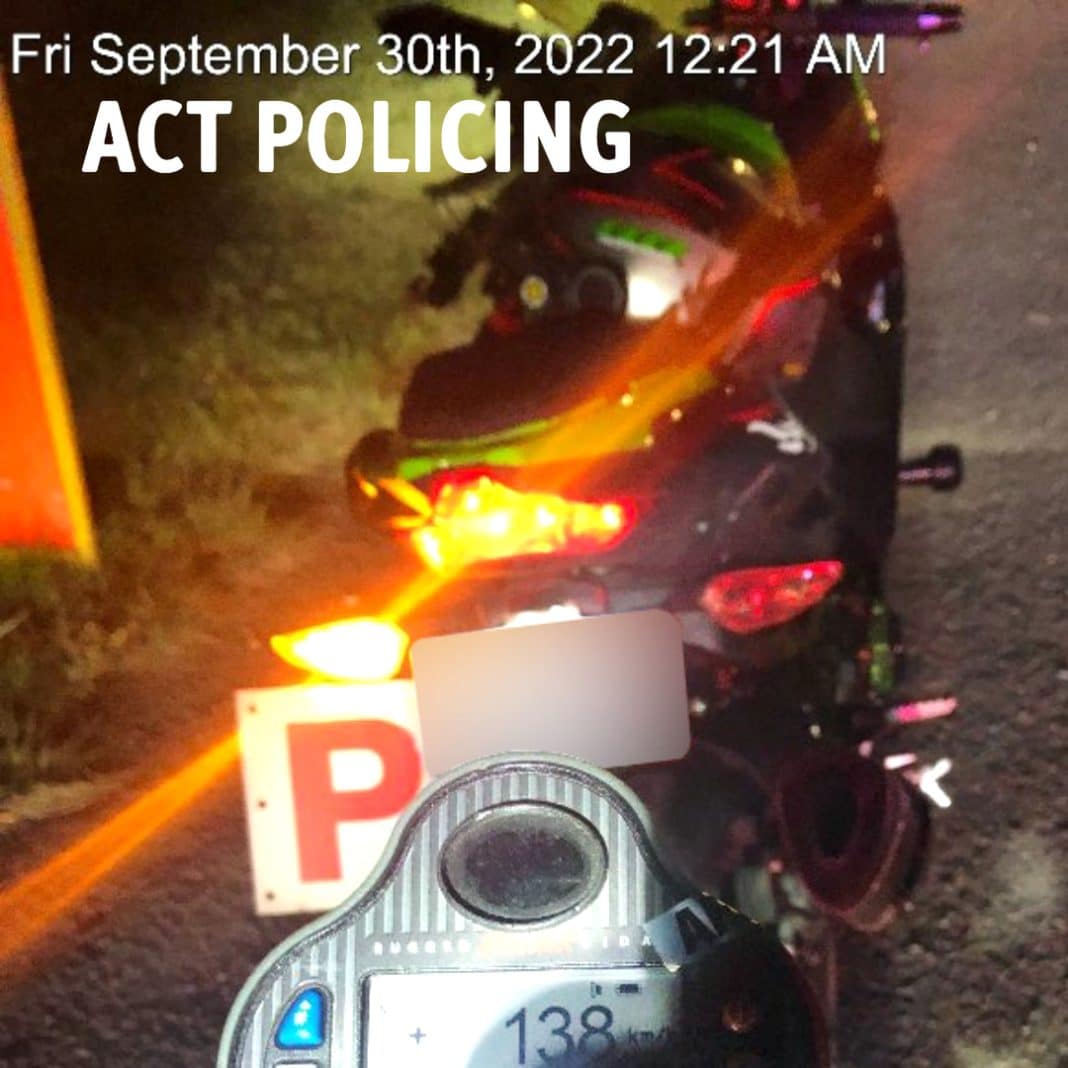 A speed camera showing 138km/h is seen near a motorbike with P plate pulled over by the roadside at night