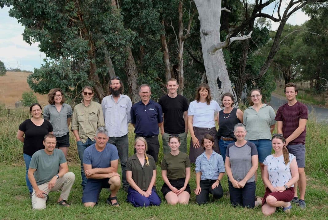 A group of 17 male and female scientists in the Australian countryside