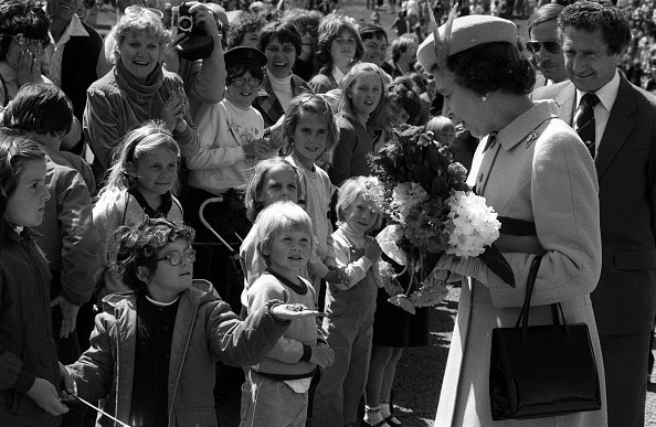 Queen Elizabeth II receives a gift from a child during her visit to Canberra