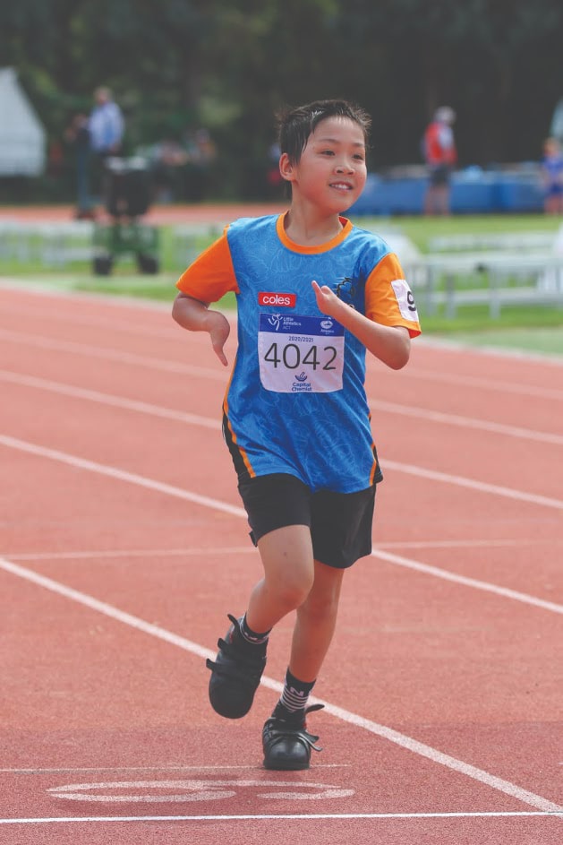 young boy running on an athletics track