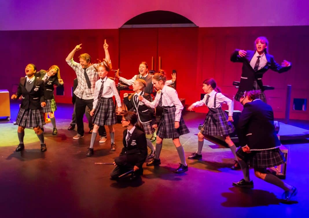 Group of young actors performing a scene from a local Canberra production of School of Rock The Musical