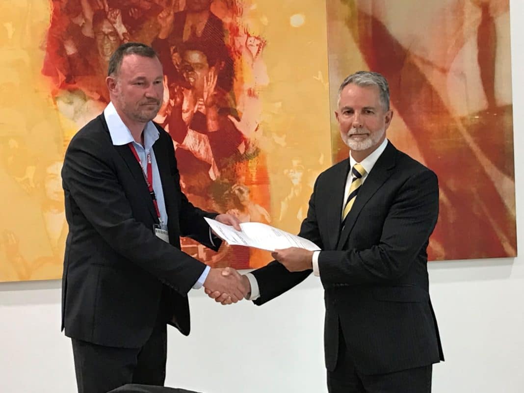 2 men shaking hands as one accepts the other's printed petitions