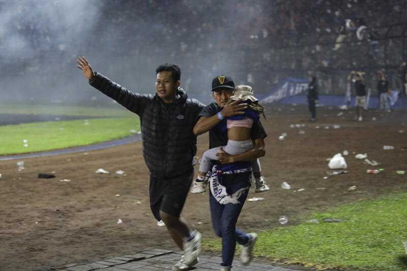 Soccer fans evacuate a girl during a clash between fans at Kanjuruhan Stadium in Malang, East Java, Indonesia, 01 October 2022