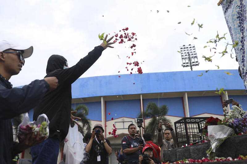 Supporters of local soccer club Arema FC throw flowers outside Kanjuruhan Stadium where riots broke out on Saturday night in Malang, East Java, Indonesia, Sunday, Oct. 2, 202