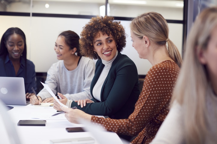 Diverse group of 5 business women meeting around a board table