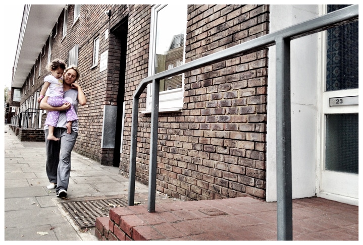 woman carrying child outside public housing flats