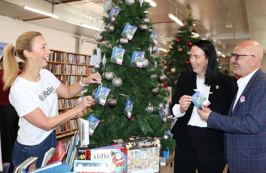2 women and 1 man hanging Lifeline Canberra donation cards on Xmas Giving Tree